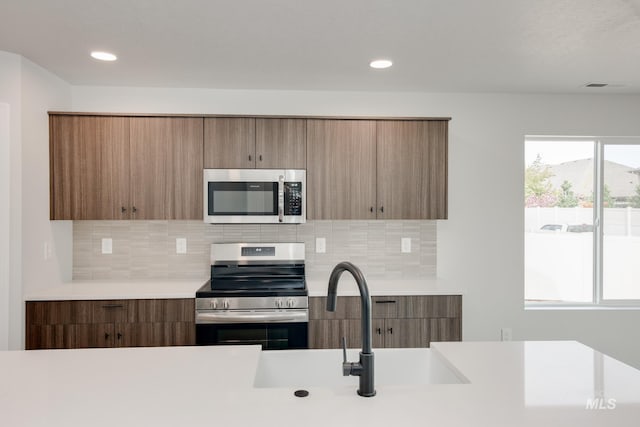 kitchen with decorative backsplash, sink, and appliances with stainless steel finishes