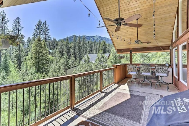 exterior space with a mountain view, a view of trees, and ceiling fan