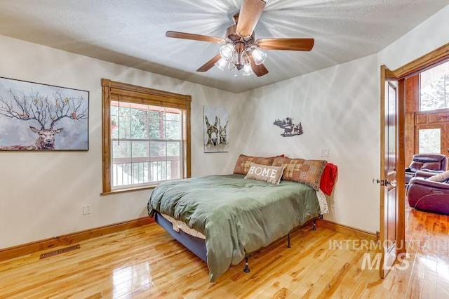bedroom with ceiling fan, baseboards, visible vents, and wood finished floors