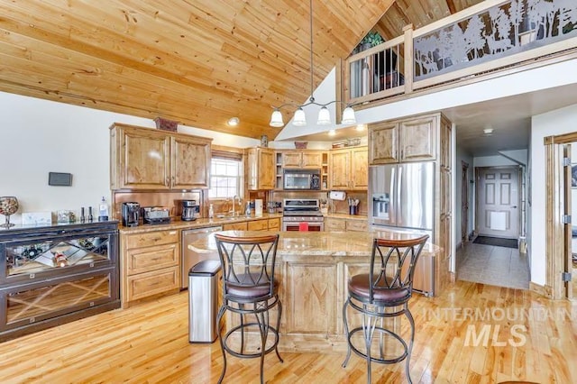 kitchen with a sink, stainless steel appliances, a kitchen breakfast bar, light wood-type flooring, and wooden ceiling