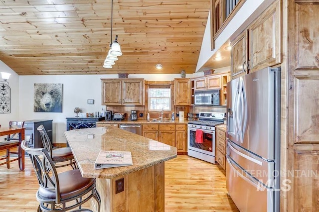 kitchen featuring light wood-style floors, stainless steel appliances, a kitchen breakfast bar, and a sink