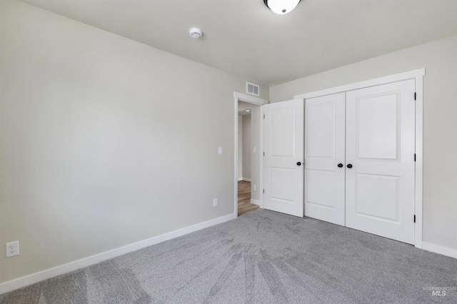 unfurnished bedroom featuring carpet flooring, baseboards, visible vents, and a closet