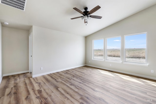 unfurnished room with visible vents, lofted ceiling, wood finished floors, baseboards, and a ceiling fan