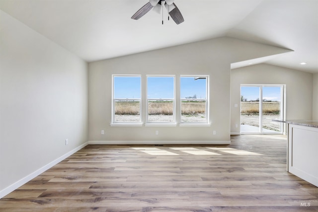 unfurnished living room with wood finished floors, baseboards, ceiling fan, and lofted ceiling