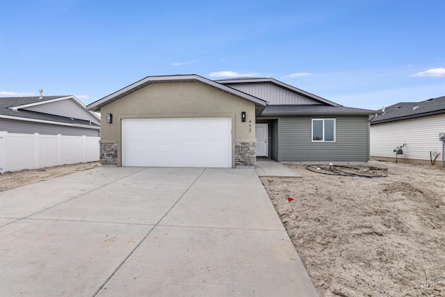 ranch-style home with an attached garage, fence, driveway, and stone siding