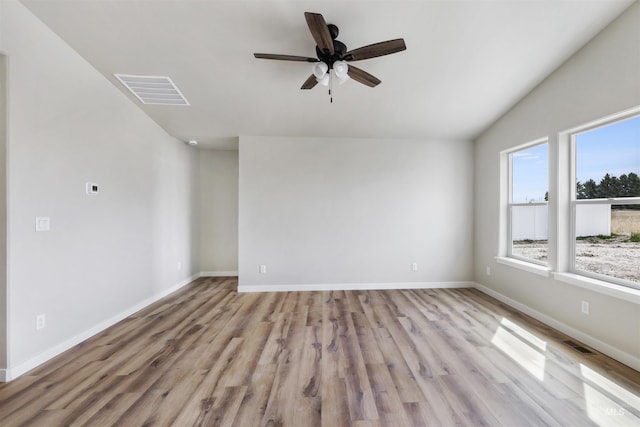 spare room with baseboards, a ceiling fan, light wood-type flooring, and visible vents