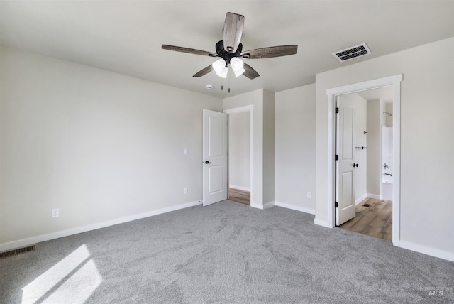 unfurnished bedroom featuring baseboards, ensuite bathroom, carpet, and visible vents