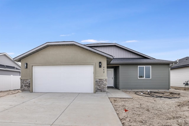 ranch-style home featuring roof with shingles, an attached garage, driveway, and stone siding