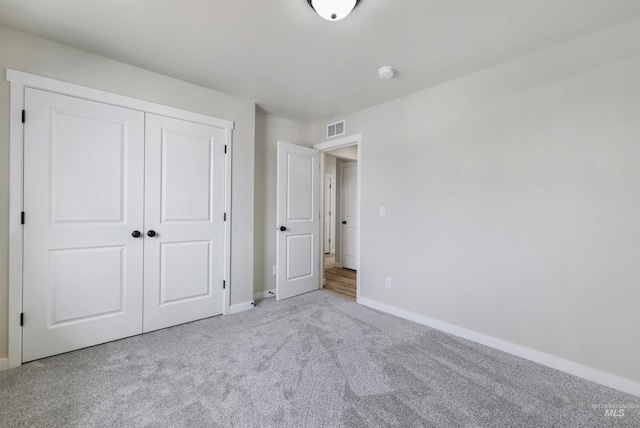 unfurnished bedroom with baseboards, visible vents, carpet, and a closet