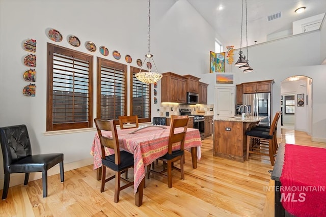 dining room with a wealth of natural light, light wood-type flooring, and high vaulted ceiling