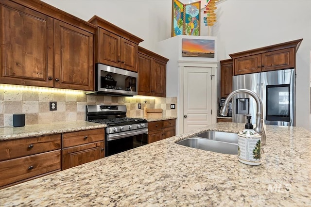 kitchen featuring light stone countertops, decorative backsplash, sink, and stainless steel appliances