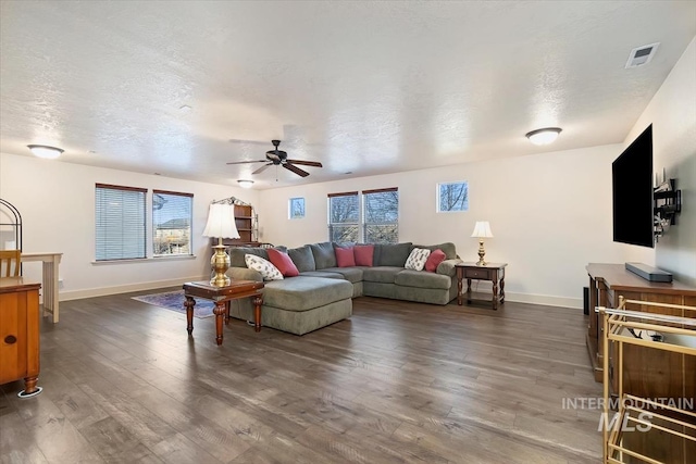 living room with a textured ceiling, dark hardwood / wood-style flooring, a wealth of natural light, and ceiling fan