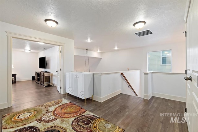 interior space featuring a textured ceiling and dark wood-type flooring