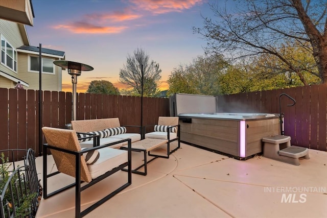 patio terrace at dusk with outdoor lounge area and a hot tub