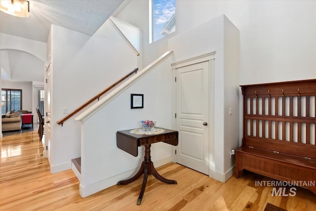 stairway featuring plenty of natural light, a textured ceiling, and hardwood / wood-style flooring