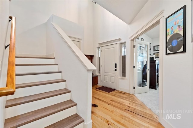 foyer entrance with wood-type flooring and vaulted ceiling