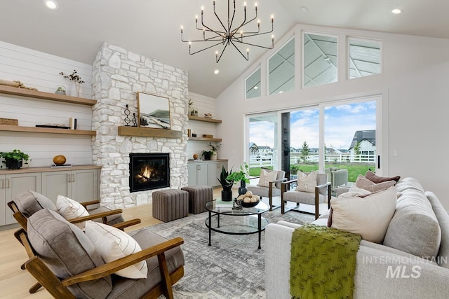 living room with a fireplace, a notable chandelier, light hardwood / wood-style flooring, and high vaulted ceiling