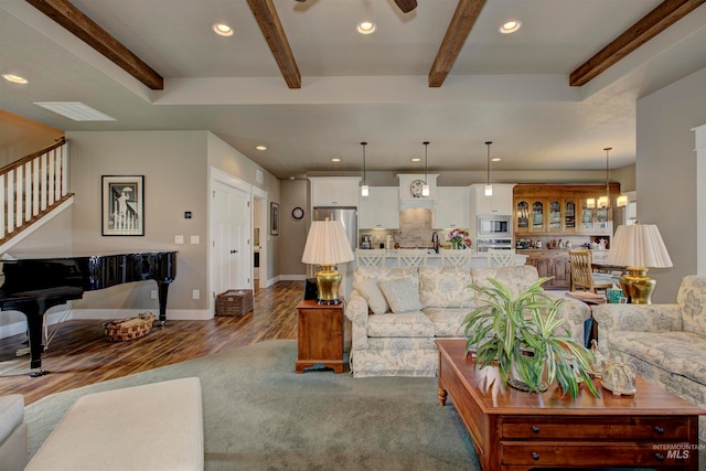 living room featuring beamed ceiling, dark hardwood / wood-style floors, and ceiling fan with notable chandelier