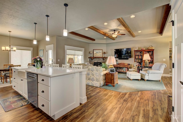 kitchen with a kitchen island with sink, a stone fireplace, pendant lighting, white cabinets, and dark hardwood / wood-style flooring