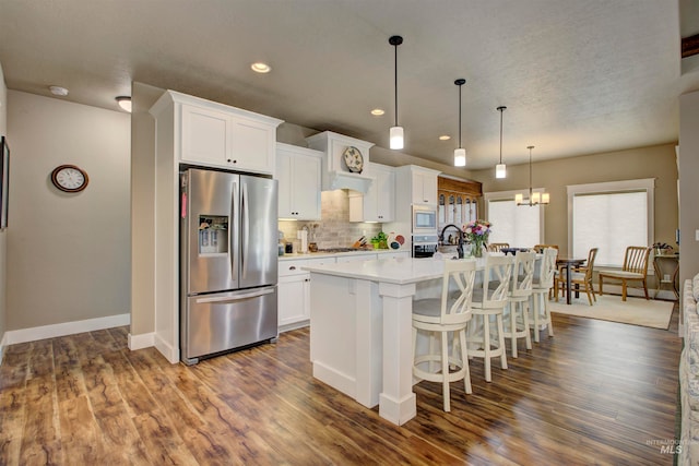 kitchen featuring dark wood-type flooring, white cabinets, stainless steel appliances, and a center island with sink