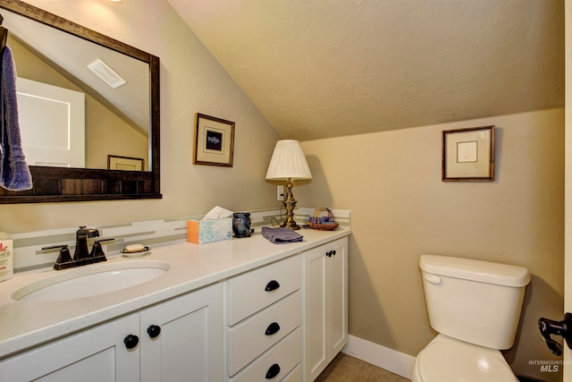 bathroom with vanity, lofted ceiling, a textured ceiling, and toilet