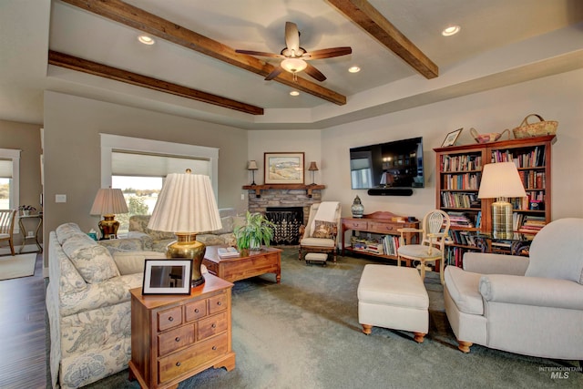 living room with dark wood-type flooring, ceiling fan, beamed ceiling, and a fireplace