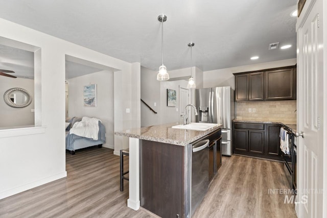 4249 W Farlam Dr, Meridian, ID 83642 - kitchen with appliances with stainless steel finishes, dark brown cabinetry, light wood-style floors, a sink, and light stone counters