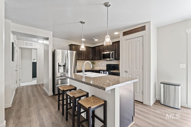 4249 W Farlam Dr, Meridian, ID 83642 - kitchen with stainless steel appliances, dark brown cabinetry, light wood-style flooring, and backsplash
