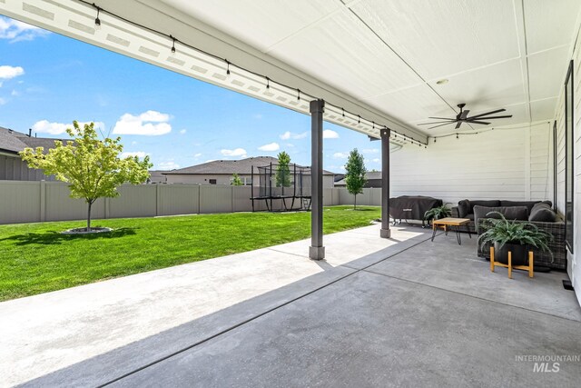 2398 N Klemmer Ave, Kuna, ID 83634 - fenced backyard with a patio area, ceiling fan, an outdoor living space, a trampoline, and a grill