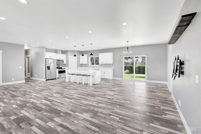 680 E 19th St, Burley, ID 83318 - unfurnished living room with light wood-type flooring, a chandelier, baseboards, recessed lighting, and a sink