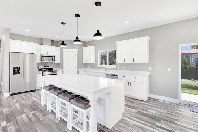 680 E 19th St, Burley, ID 83318 - kitchen featuring appliances with stainless steel finishes, a center island, light countertops, light wood finished floors, and plenty of natural light