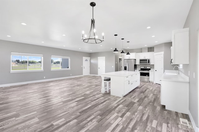 680 E 19th St, Burley, ID 83318 - kitchen with stainless steel appliances, light wood-style floors, a sink, a kitchen island, and a kitchen bar