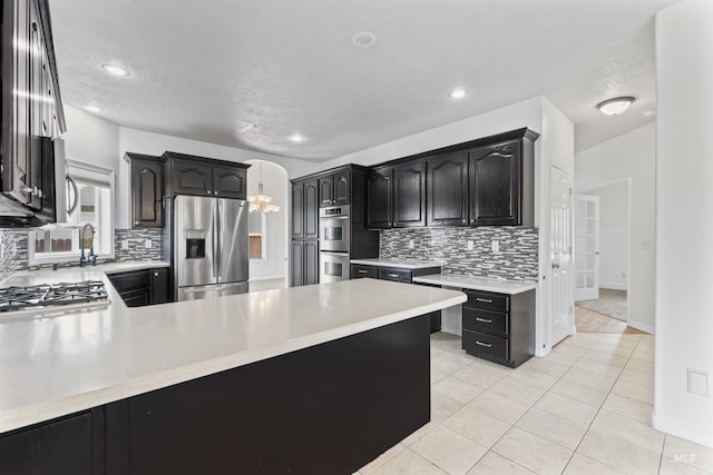 1992 S Elkhound Ave, Meridian, ID 83642 - kitchen featuring stainless steel appliances, tasteful backsplash, light countertops, arched walkways, and light tile patterned floors