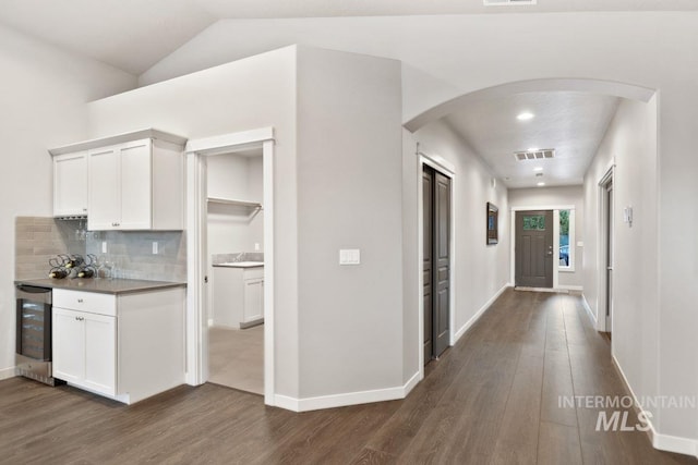 hall featuring dark wood-type flooring, lofted ceiling, and beverage cooler