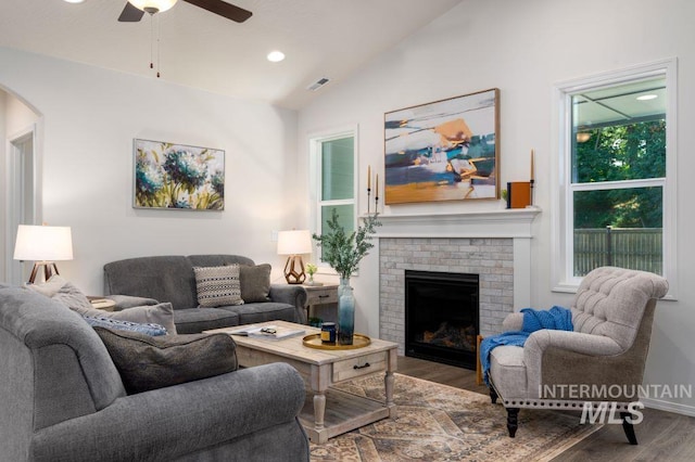 living room with ceiling fan, wood-type flooring, lofted ceiling, and a brick fireplace