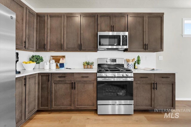 kitchen featuring stainless steel appliances, light hardwood / wood-style floors, and decorative backsplash