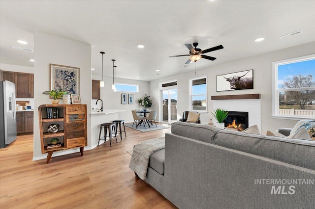 living room featuring light hardwood / wood-style flooring, ceiling fan, and plenty of natural light