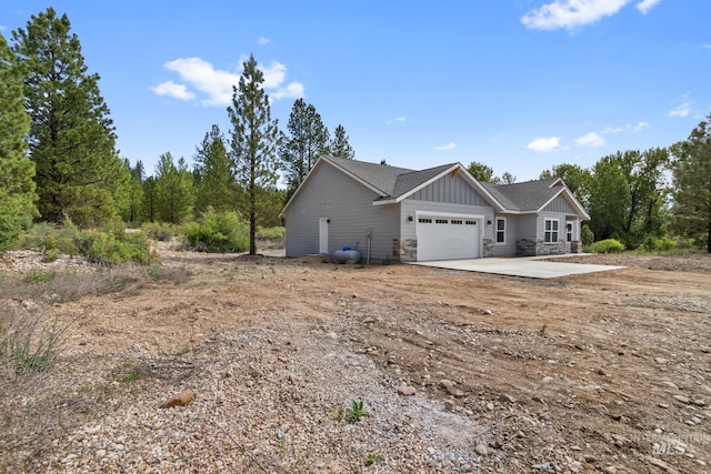 207 Lainey Ln, Idaho City, ID 83631 - view of side of property featuring board and batten siding, concrete driveway, an attached garage, and stone siding