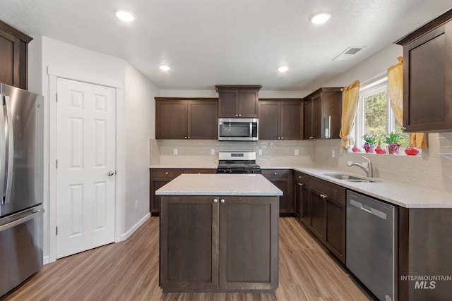 207 Lainey Ln, Idaho City, ID 83631 - kitchen with appliances with stainless steel finishes, dark brown cabinets, a kitchen island, light wood finished floors, and backsplash