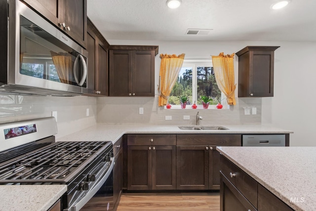 207 Lainey Ln, Idaho City, ID 83631 - kitchen featuring stainless steel appliances, dark brown cabinets, backsplash, light wood-style floors, and recessed lighting