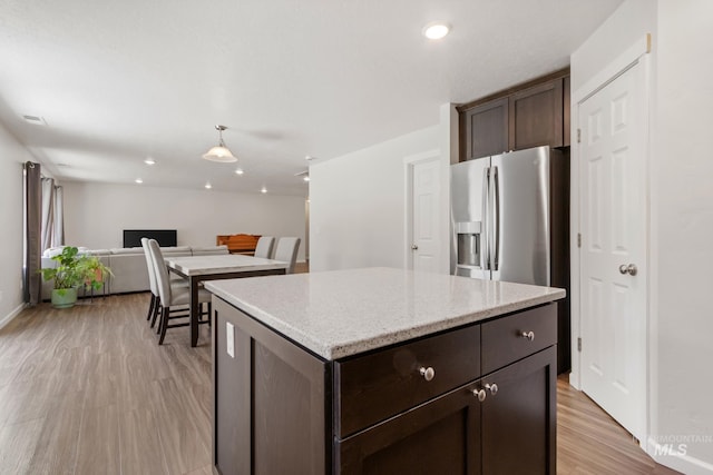 207 Lainey Ln, Idaho City, ID 83631 - kitchen with light wood finished floors, dark brown cabinets, a kitchen island, stainless steel fridge with ice dispenser, and light stone countertops