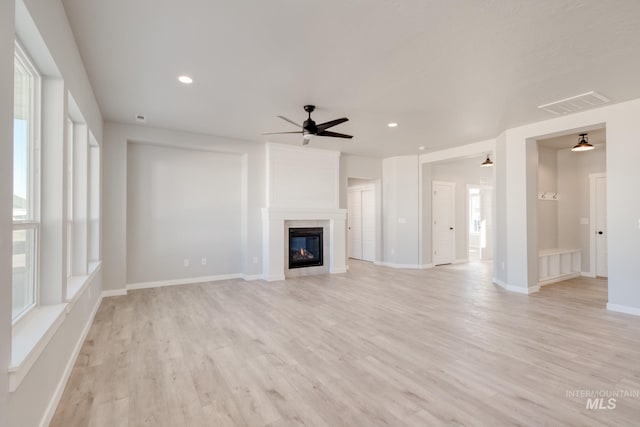 unfurnished living room featuring light wood-type flooring, recessed lighting, visible vents, and a glass covered fireplace