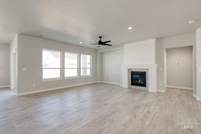 unfurnished living room featuring light wood-type flooring, baseboards, and a tile fireplace