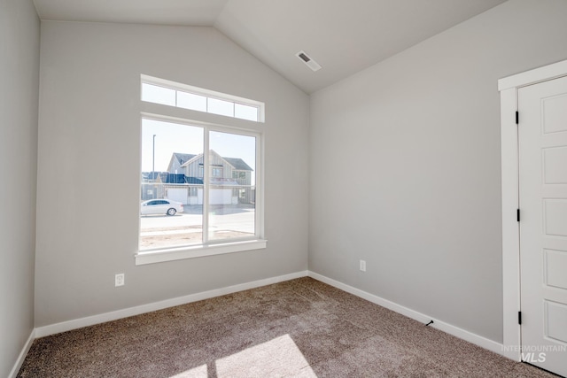 carpeted spare room featuring lofted ceiling, visible vents, and baseboards