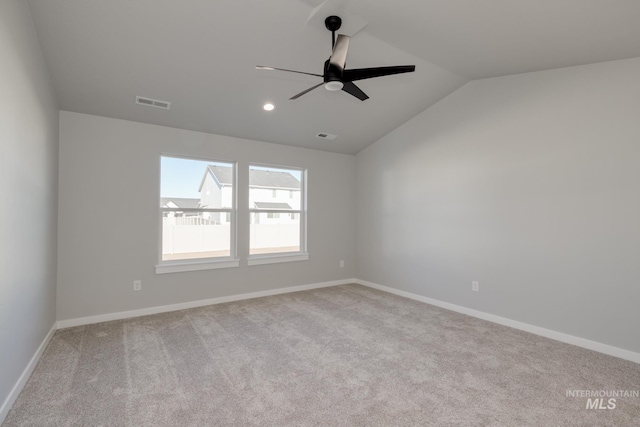 empty room featuring lofted ceiling, visible vents, carpet flooring, ceiling fan, and baseboards