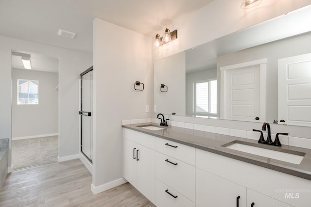 full bathroom featuring baseboards, a sink, visible vents, and a shower stall