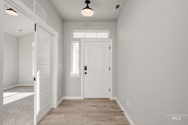 foyer with light wood-type flooring, visible vents, and baseboards