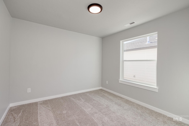 carpeted spare room with visible vents and baseboards