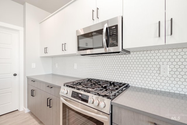 kitchen with light wood finished floors, stainless steel appliances, tasteful backsplash, and light countertops