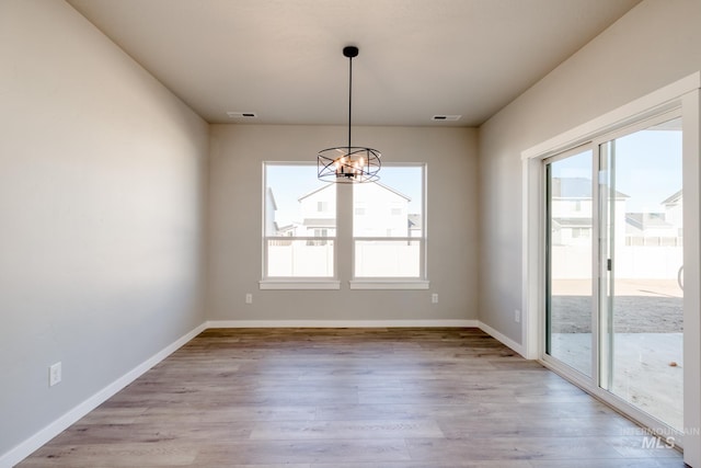 unfurnished dining area with baseboards, light wood-style flooring, visible vents, and a notable chandelier